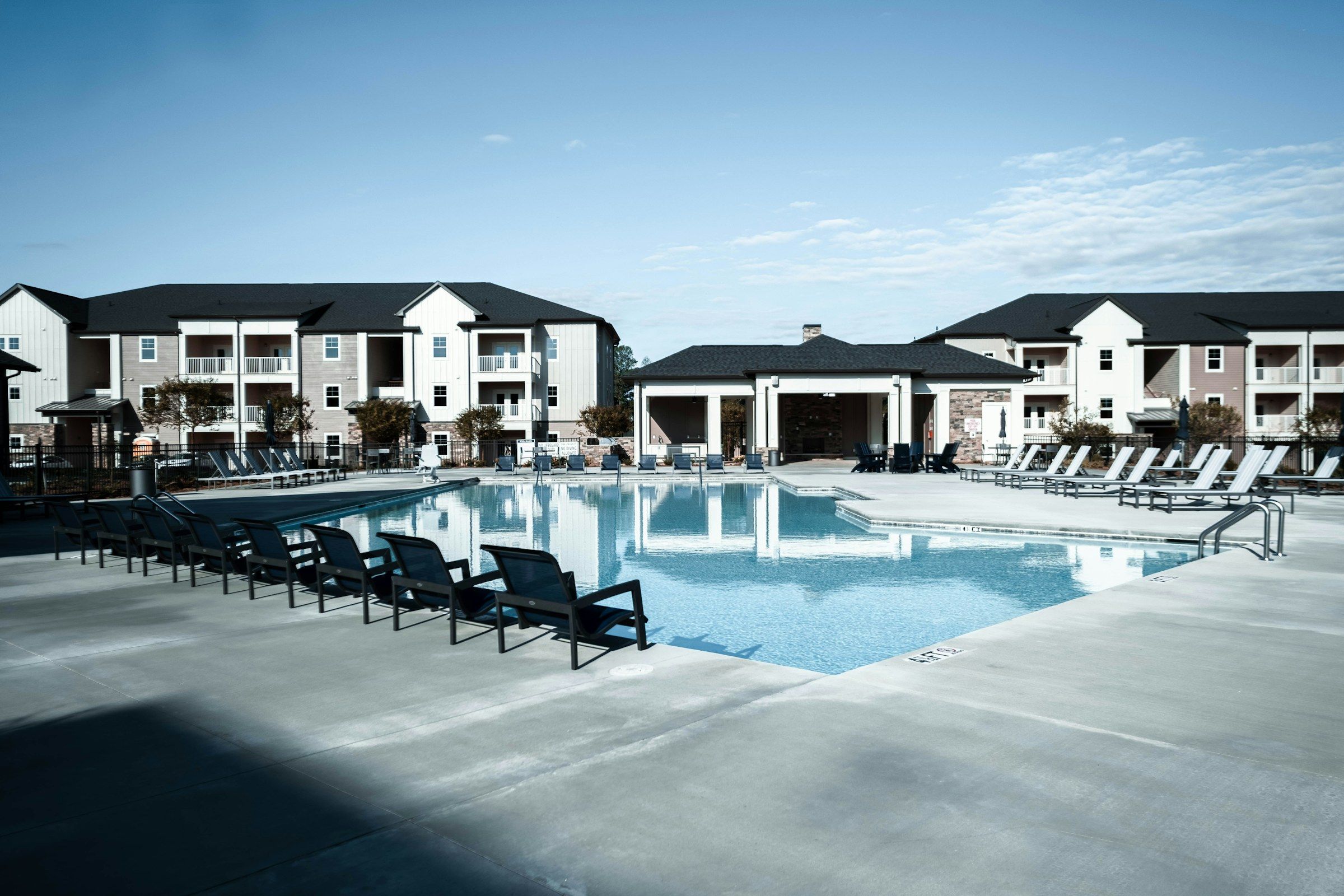 Apartment community with a swimming pool and lounge chairs