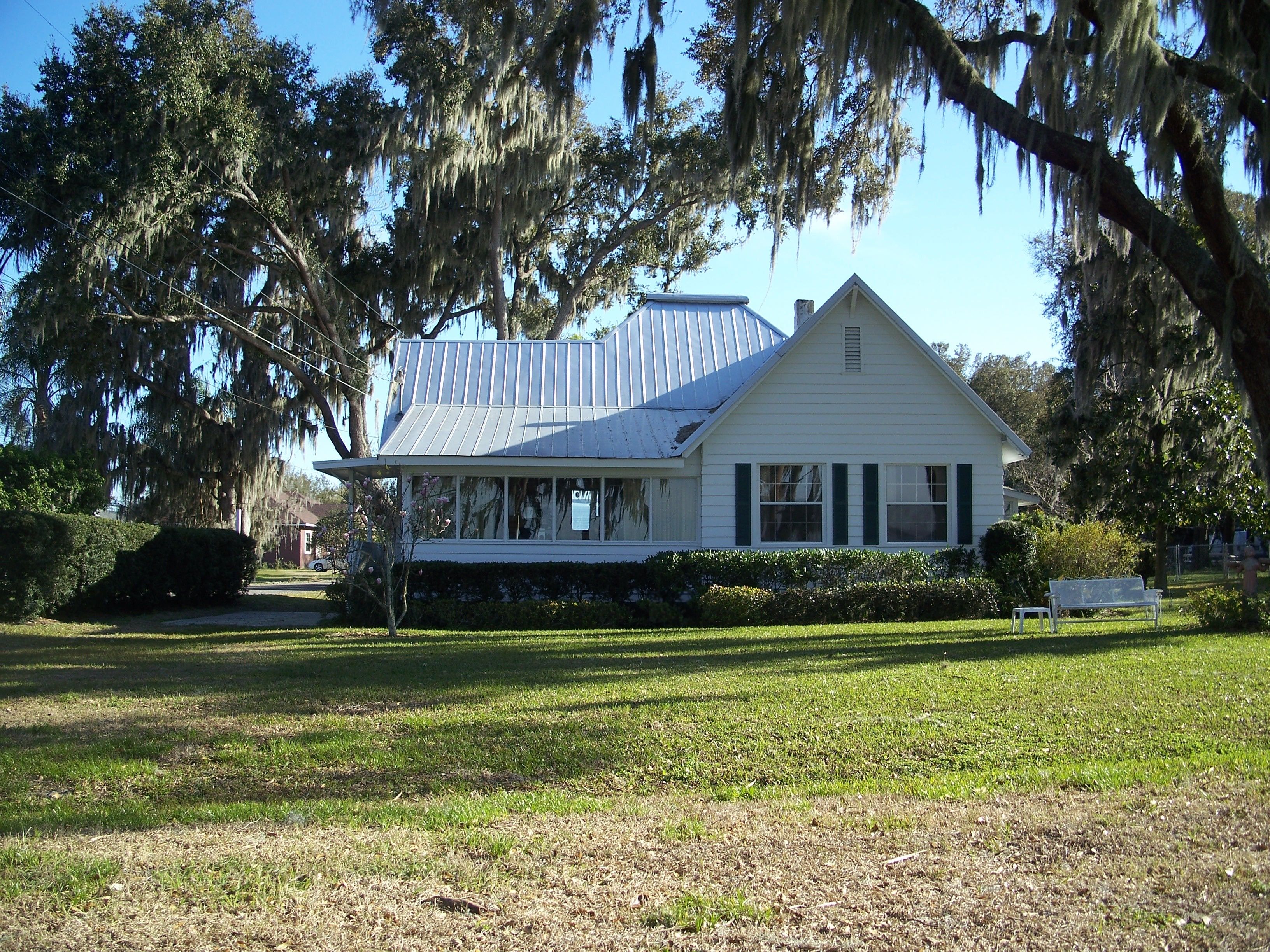 White old-Florida cottage with a metal roof under moss-draped live oaks in Yalaha, Lake County